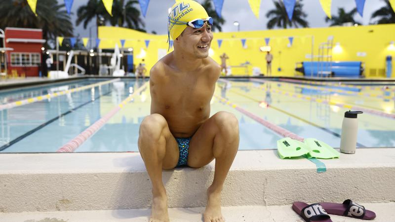 Mohammad Abbas Karimi smiling while sitting next to a swimming pool