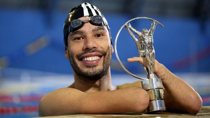 A man in a swimming pool posing with the Laureus Awards