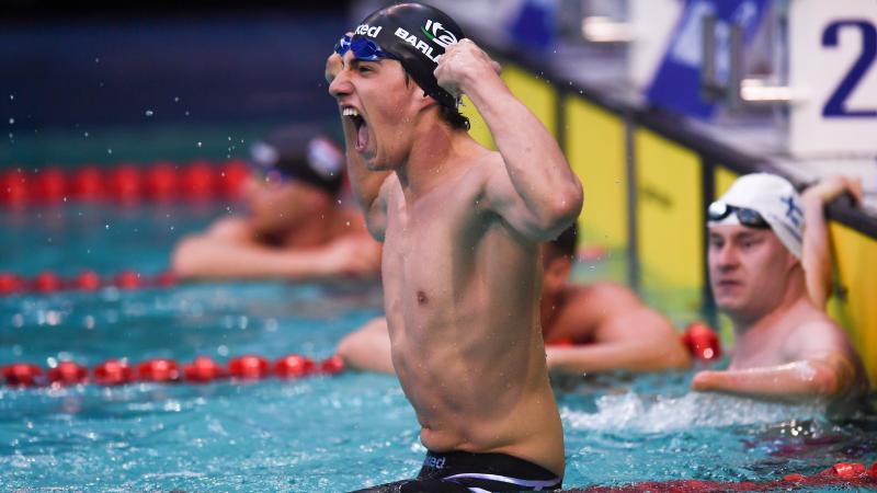 A swimmer celebrating in the pool observed by another swimmer