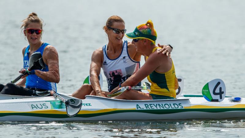 Two women in kayaks congratulate each other after a race