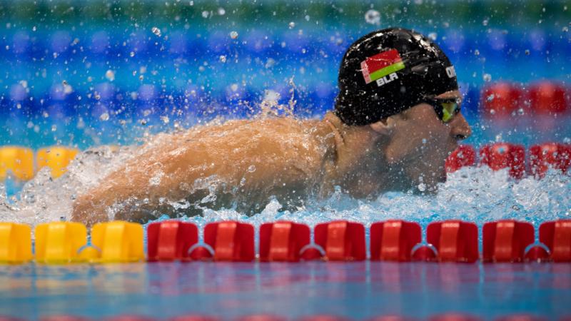 A man with a black cap swimming in a pool