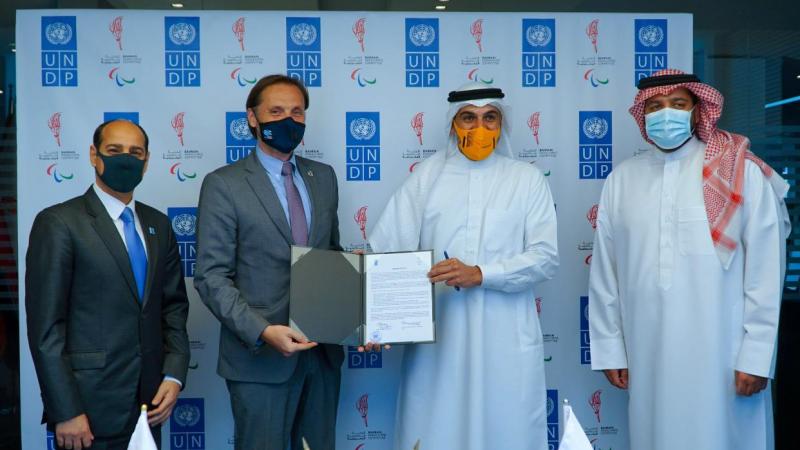 Group of men posing for photo holding  signed agreement