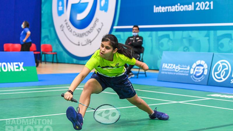 Young female badminton player with left arm impairment lunges for the shuttle