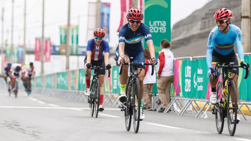 Argentine cyclists smiles after crossing the road race finish line first as Colombian cyclist who came second smiles to her