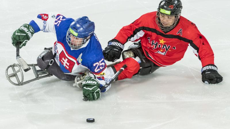 A Para ice hockey player with the uniform of Slovakia playing against another player from China