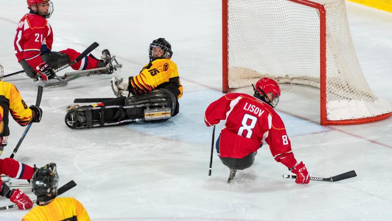 A Para ice hockey player scoring a goal observed by other four players