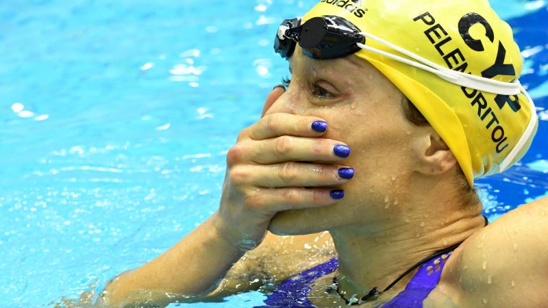 A woman in a swimming pool with a hand in her mouth as in surprise