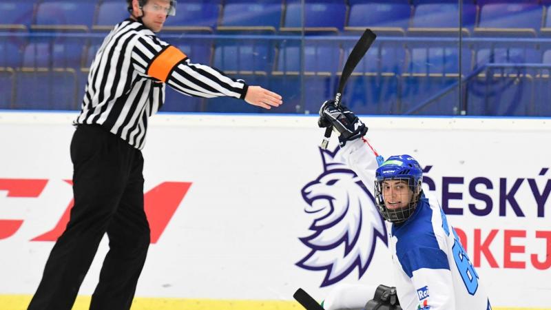 An ice hockey in sledges on an ice rink near a referee