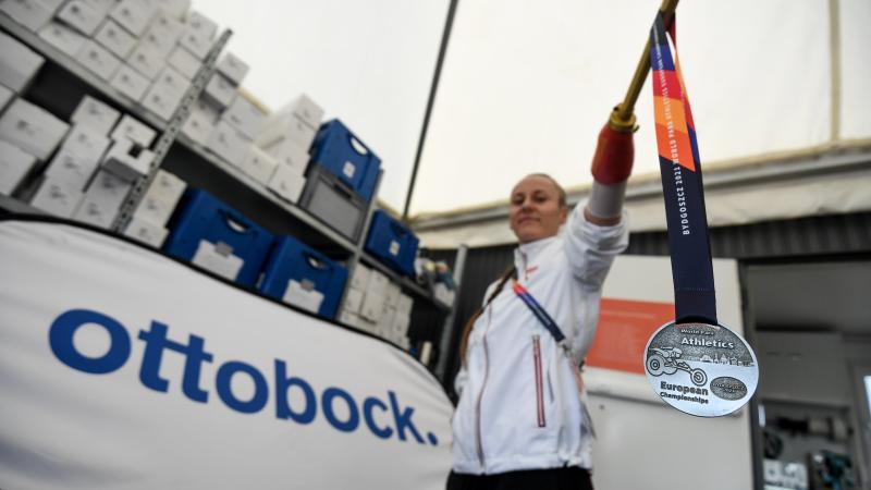 A woman with a prosthetic arm holding a silver medal