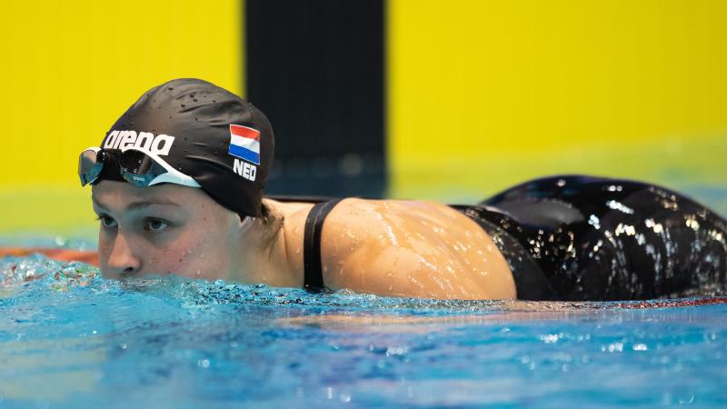 A woman with a black swimming cap putting her head out of the water