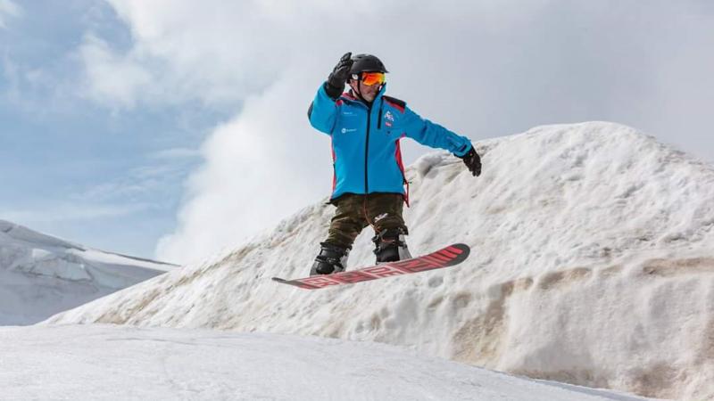 A double-leg amputee man practicing snowboard 