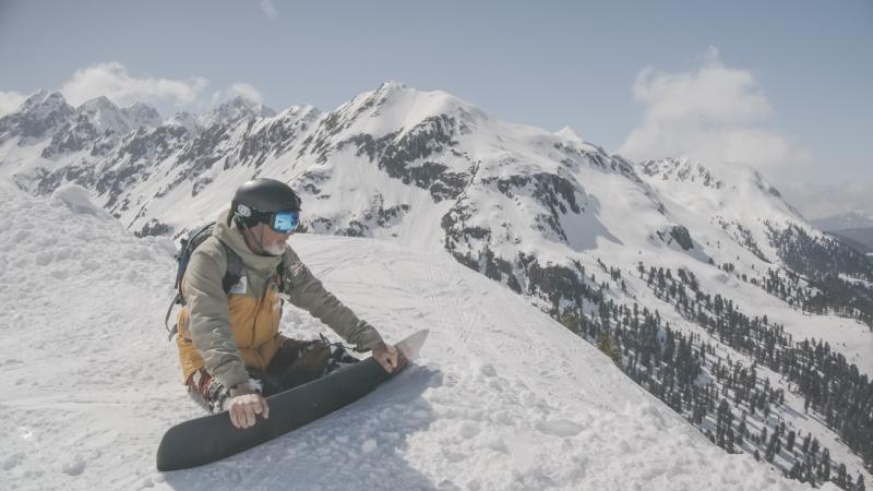 A male Para snowboarder watching the mountain