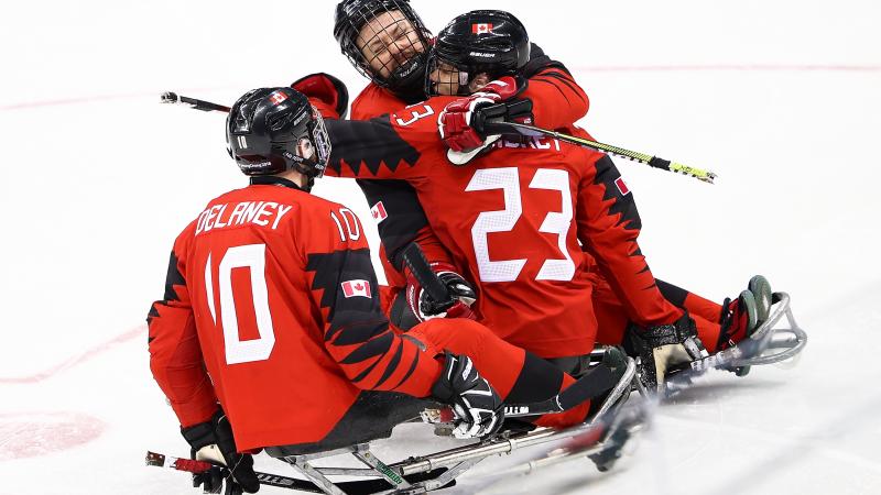 Three Canadian Para ice hockey players hugging in celebration during a game