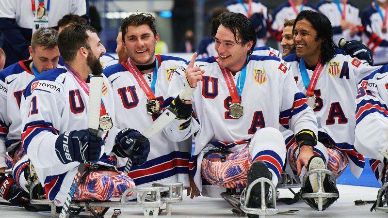 A group of USA Para ice hockey players with their gold medals on an ice rink