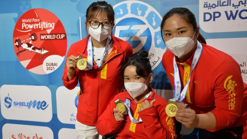 Three women with the uniform of China showing their gold medals