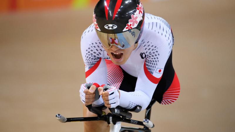 Cyclist with one leg wearing Japanese gear opens his mouth as he makes an effort during a sprint