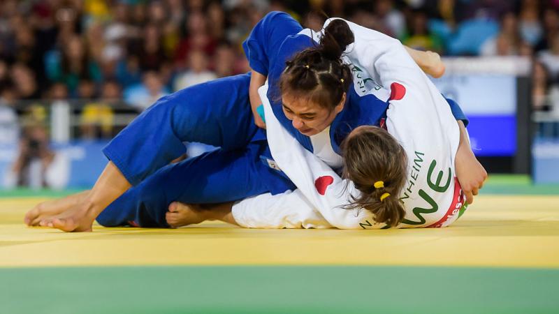 A women pins down her opponent on the judo mat