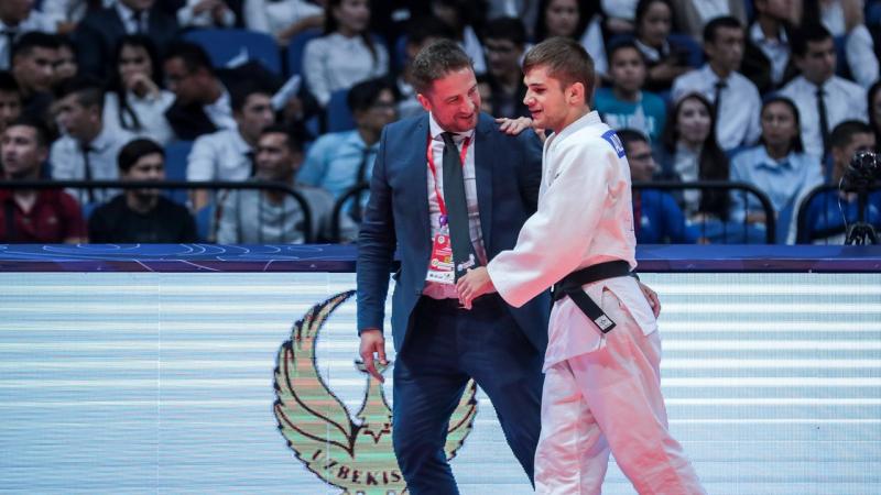 Judo coach guides blind judoka off the mat