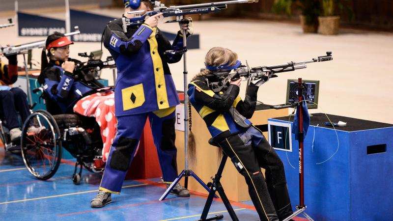 Three female athletes shooting a rifle in a range