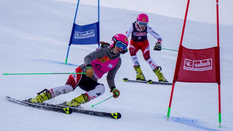 A female skier following her guide in a Para alpine skiing race
