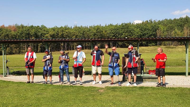 Seven men standing on a shotgun shooting range on a sunny day