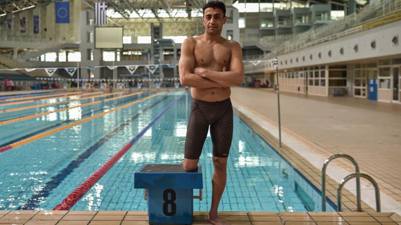 Swimmer Ibrahim Al Hussein posing in front of the pool while wearing his swimsuit