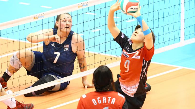 Chinese player sets the volleyball as USA opponent watches on the other side of the net