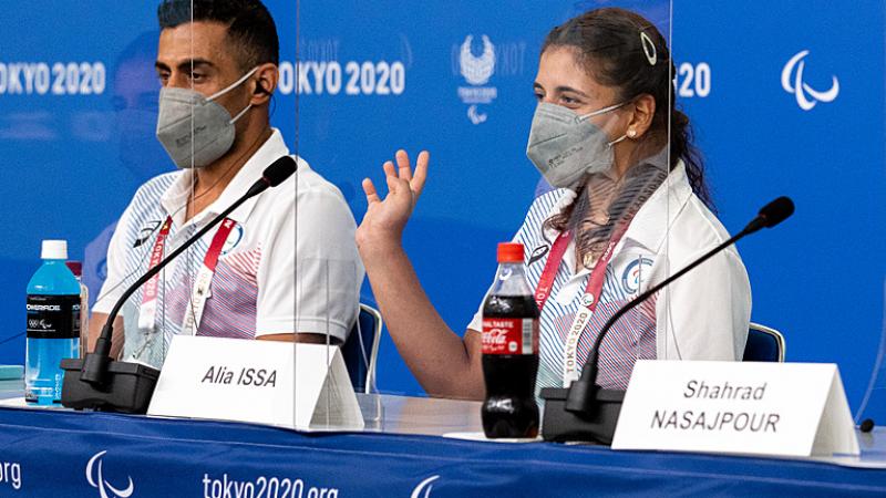 A man and a woman in a press conference wearing face masks