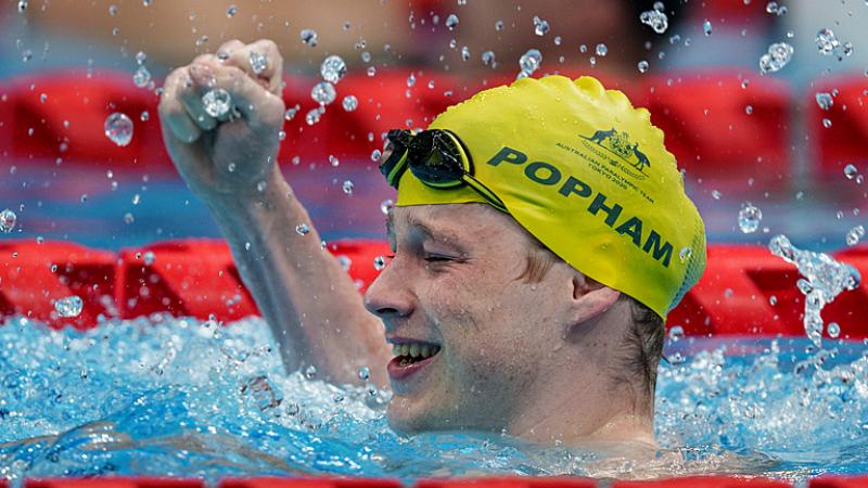 A man celebrating in the swimming pool with his fist high