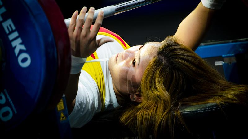 A woman putting her hands around a bar on a bench press