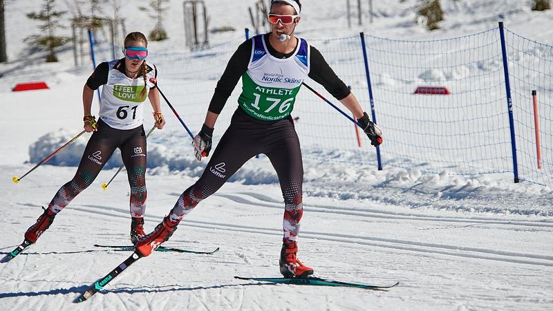 A female Para cross-country skier following her male guide during a competition