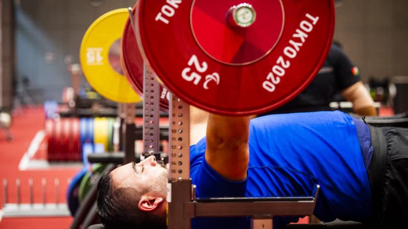 A man with a blue shirt practicing on a bench press