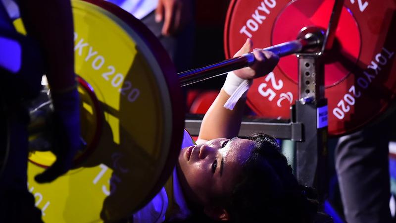 A woman preparing to lift the bar on a bench press competition