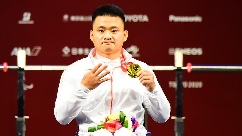 A man showing his medal and four fingers in a hand