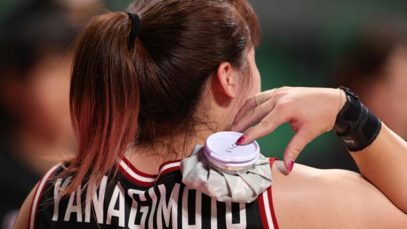 Woman puts ice pack on shoulders