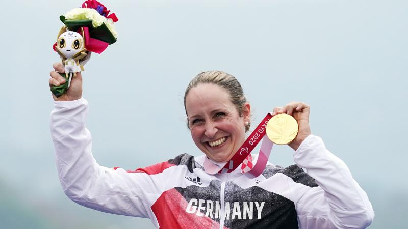 German cyclist Annika Zeyen on the podium holding the gold medal with a smile from ear-to-ear