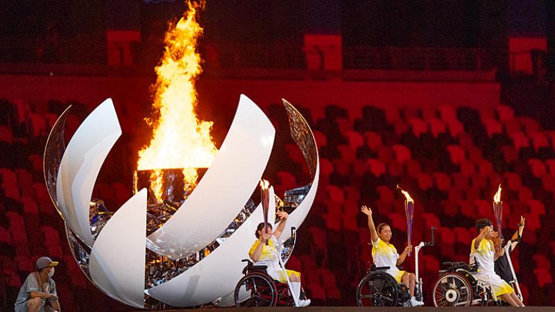 Japanese Para athletes Yui Kamiji, Shunsuke Uchida and Karin Morisaki turn and wave after lighting the Tokyo 2020 Paralympic Flame