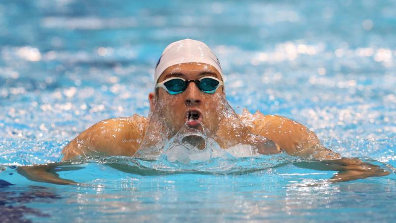 A man swims in the pool with the goggles and swimming cap