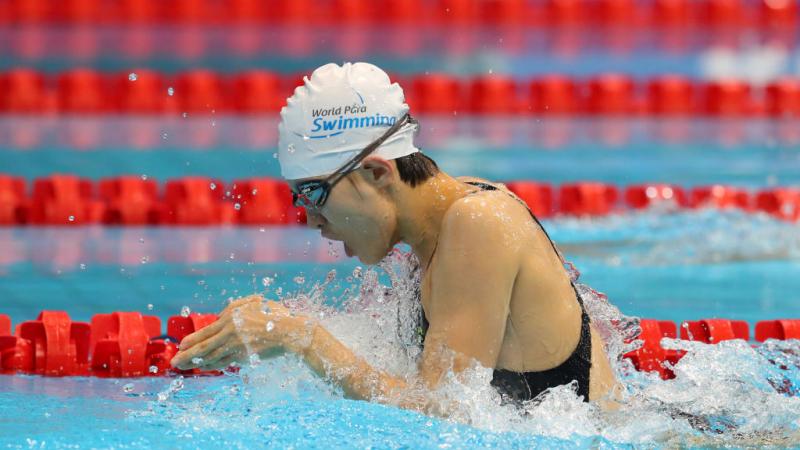 A female swimmer in the pool swimming in the breaststroke style