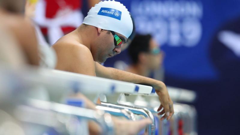 A man sits on the edge of the pool waiting for his race to start