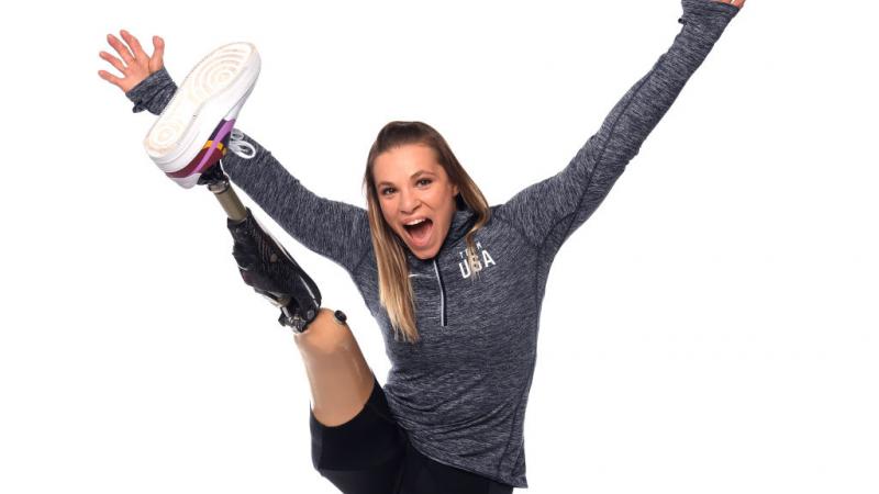 A woman stretching her prosthetic leg and smiling