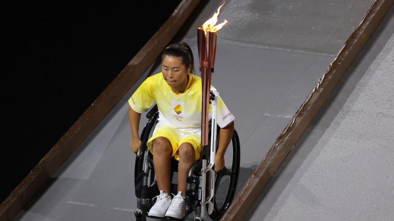 Yui Kamiji goes down ramp holding Paralympic flame at Opening Ceremony