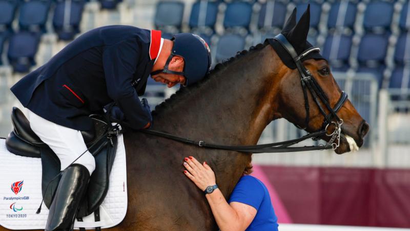 Lee Pearson lays his head on his horse