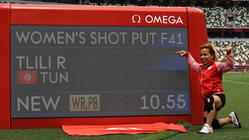 A woman pointing at a screen showing her world record mark in a stadium