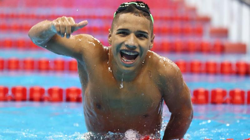 A man in the pool smiles with a thumbs up 