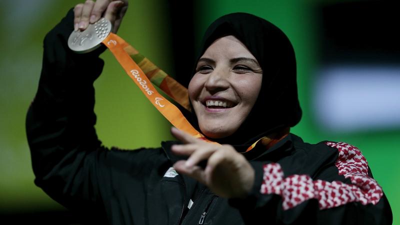 A woman with a veil smiling and showing her medal