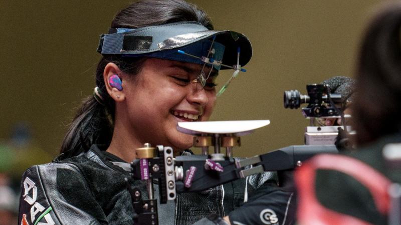 Female Indian shooting athlete smiles