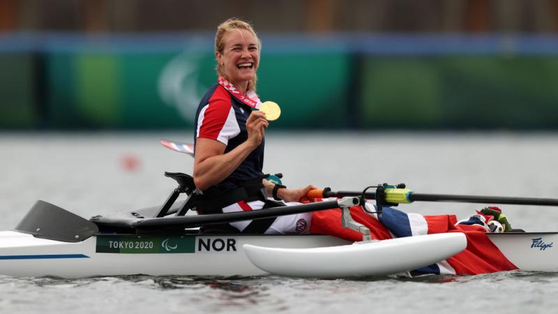 Female rower on her boat celebrates gold medal