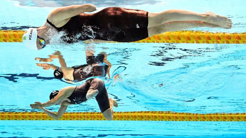 Two women with limb impairments swimming side by side 