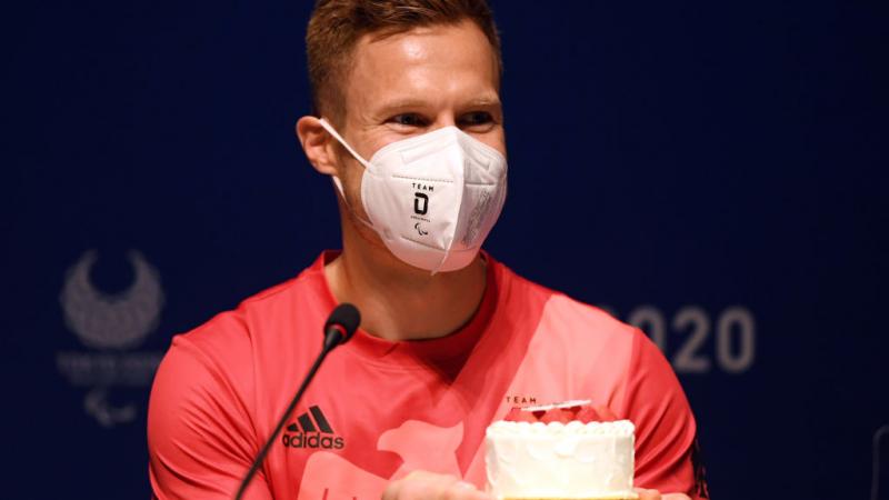 Man with mask on accepts birthday cake